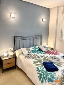 a bedroom with a large bed with a blue and white blanket at APARTBEACH TURQUESA BJ CLIMATIZADO JUNTO PLAYA y PISCINAS in La Pineda