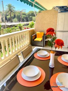 two tables with plates and a vase with flowers on a balcony at APARTBEACH TURQUESA BJ CLIMATIZADO JUNTO PLAYA y PISCINAS in La Pineda