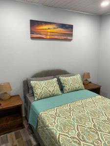 a bedroom with a bed and two nightstands and a painting at Carnbee Cozy Cottage in Bethel