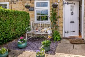 a white bench sitting outside of a house with potted plants at Snowdrop Cottage in Wetherby