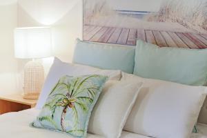 ein Bett mit einem Haufen Kissen drauf. in der Unterkunft Rosie's Seaview-Lake to ocean view in Merimbula