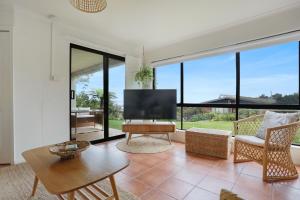 ein Wohnzimmer mit einem TV und einem großen Fenster in der Unterkunft Rosie's Seaview-Lake to ocean view in Merimbula