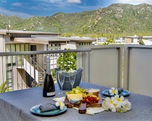 a table with food and a bottle of wine on a balcony at Bright Point 1308 at Magnetic in Nelly Bay