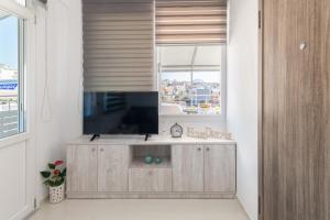 uma sala de estar com televisão e janela em Rooftop Cosy Apartment Perfect Location em Heraclião