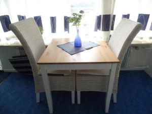 a wooden table with two chairs with a vase on it at Ferienpark Sierksdorf App 773 - Strandlage in Sierksdorf