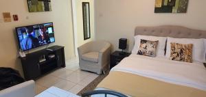a bedroom with a bed and a tv and a chair at Hastings Towers 4D - Studio Apt Opp Beach in Bridgetown