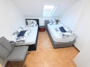 ein kleines Zimmer mit 2 Betten und einem Stuhl in der Unterkunft FMI44Apartment in Rüsselsheim