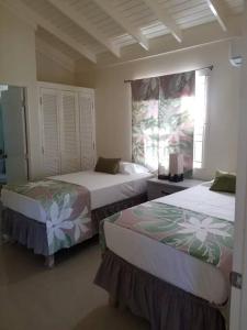 a bedroom with two beds and a window at Villa verde Jamaica - Oceanview Getaway, Gated & Secured in Falmouth