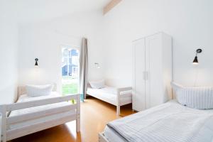 Habitación blanca con 2 camas y espejo. en Strandpark Sierksdorf H059, en Sierksdorf