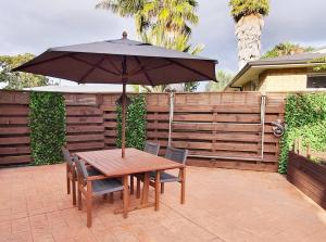 een houten tafel met een parasol op een patio bij Central Oasis in Tauranga