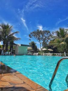 une grande piscine bleue avec des chaises et des palmiers dans l'établissement Pousada caminho da fé, à Aparecida