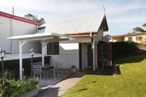 a patio with a table and a white roof at Tuross Head Motel in Tuross Heads