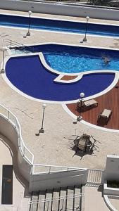 einen großen Pool mit einem Tisch und Stühlen in der Unterkunft Apartamento com vista pro mar in Bertioga
