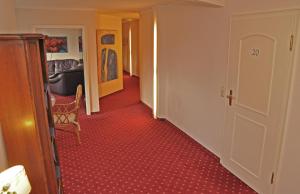 um corredor com piso alcatifado vermelho e um quarto em Hotel Garni Kristinenhof em Bad Zwischenahn