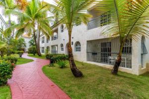 una casa con palmeras frente a una pasarela en Cozy 2 bdr condo, with pool area and free WIFI, en Punta Cana