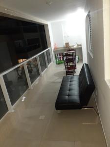 ein Wohnzimmer mit einer schwarzen Couch und einem Tisch in der Unterkunft Apartamento com vista pro mar in Bertioga
