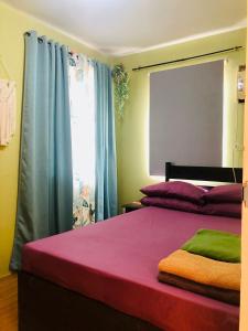 1 dormitorio con 1 cama de color morado y verde en Downtown Prominenza 844, en Baliuag