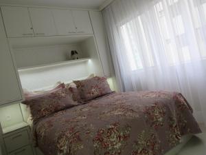 um pequeno quarto com uma cama e uma janela em AP 507 UMA QUADRA DO MAR no Balneário Camboriú