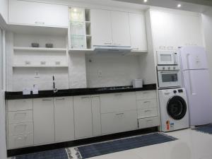 cocina con armarios blancos, lavadora y secadora en AP 507 UMA QUADRA DO MAR en Balneário Camboriú