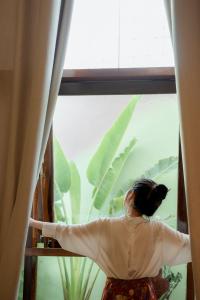 Eine Frau, die aus dem Fenster schaut auf eine Pflanze in der Unterkunft La Luna Quy Nhon in Quy Nhon