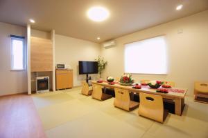 een woonkamer met een tafel en stoelen en een televisie bij SAKURA Jozankei ZEN in Jozankei