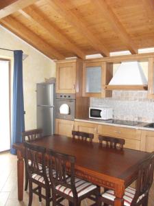 eine Küche mit einem Holztisch mit Stühlen und einem Kühlschrank in der Unterkunft Agriturismo Il Sorriso dei Figli in Argegno