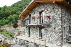 a stone house with flowers on the balcony at Agriturismo Il Sorriso dei Figli in Argegno
