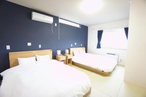 een slaapkamer met 2 witte bedden en een blauwe muur bij SAKURA Jozankei ZEN in Jozankei