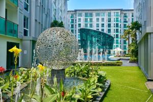 a fountain in a garden in a city with buildings at City Center Residence by Tech in Pattaya Central