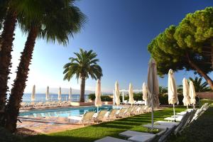 una piscina con sedie, ombrelloni e oceano di Hôtel Les Mouettes - Teritoria ad Ajaccio