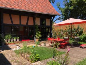 Bourgheim的住宿－B&B Le Lodge，一个带红色桌子和遮阳伞的庭院