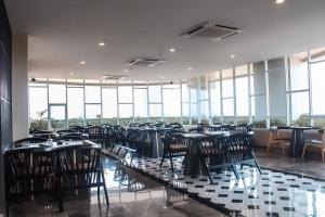 a dining room with tables and chairs and windows at BeSS Mansion Hotel Surabaya in Wonocolo