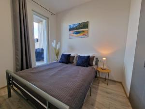 a bedroom with a bed with blue pillows and a window at MANO JŪRA 2 SILVER in Palanga +22 photos