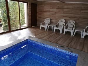 Habitación con piscina con sillas y mesa. en Къща за гости Мира en Strelcha