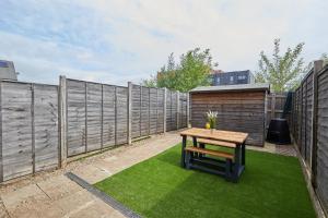 a backyard with a wooden table and a fence at Royal Derby Hospital 2 Bed Town House in Derby