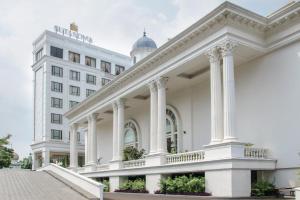 a large white building with columns at Sutasoma Hotel in Jakarta