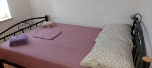 a bed with purple sheets and towels on it at Apartman JADRANKO Murter in a quiet environment near the center and the beach in Murter