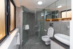 a bathroom with a toilet and a glass shower at CySuites Apartment Hotel in Nairobi