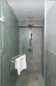 a bathroom with a shower with a white towel at CySuites Apartment Hotel in Nairobi