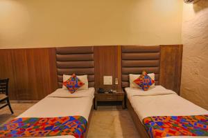 Habitación con 2 camas y mesa. en FabHotel Surya en Bhopal