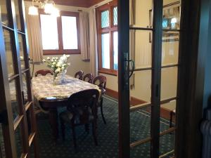 a dining room with a table with a vase of flowers on it at Grand On Victoria in Hawera