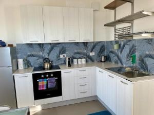 a kitchen with white cabinets and a blue and white wallpaper at villetta Sole Mare in Santo Stefano al Mare