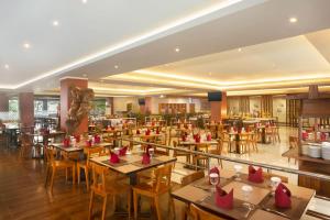 a restaurant with tables and chairs and a bar at Merapi Merbabu Hotel Yogyakarta Powered by Archipelago in Yogyakarta