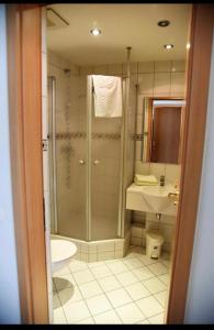 a bathroom with a shower and a toilet and a sink at Hotel Normandie in Schildow