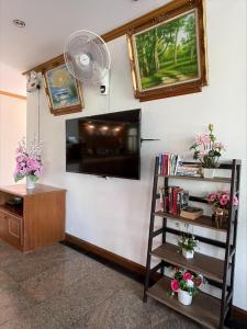 a living room with a television and a book shelf at Krabi Golden Hill Hotel in Krabi