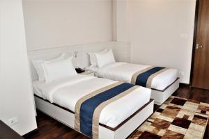 two beds in a room with white walls and wood floors at Hotel Mega & Apartment in Kathmandu