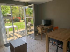 uma sala de estar com uma mesa e uma televisão e uma porta de vidro deslizante em Cottage 102 em Saumur