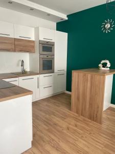 a kitchen with white cabinets and a green wall at Apartament na Mazowieckiej in Kołobrzeg