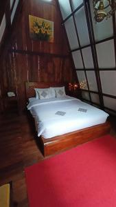 Bliss family cottage Batu في باتو: غرفة نوم بسرير كبير مع سجادة حمراء