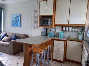 a kitchen with a counter and stools in a room at South Coast Riviera - 805 in Port Shepstone